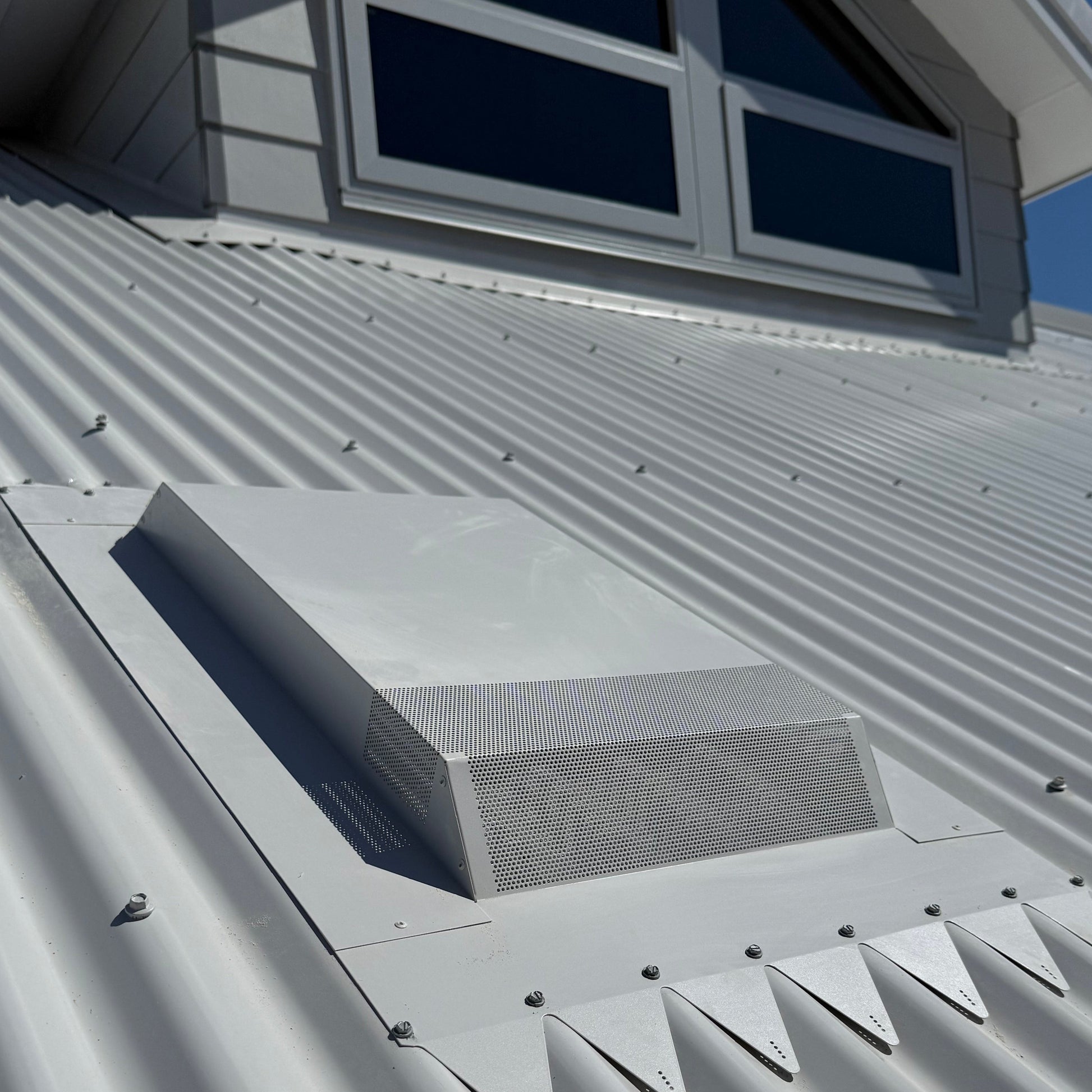 A low profile range hood roof vent installed on a corrugated metal roof.