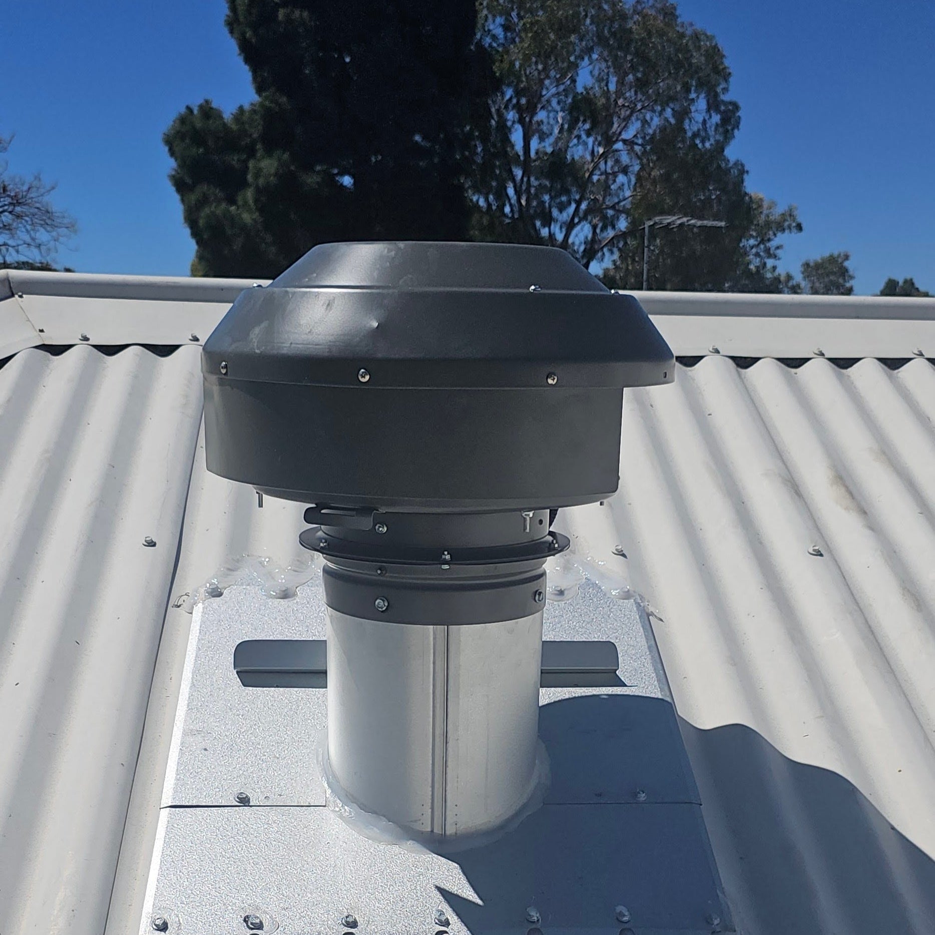 RK200 universal 200mm metal roof flume installed with an external rangehood roof motor on a corrugated tin roof.